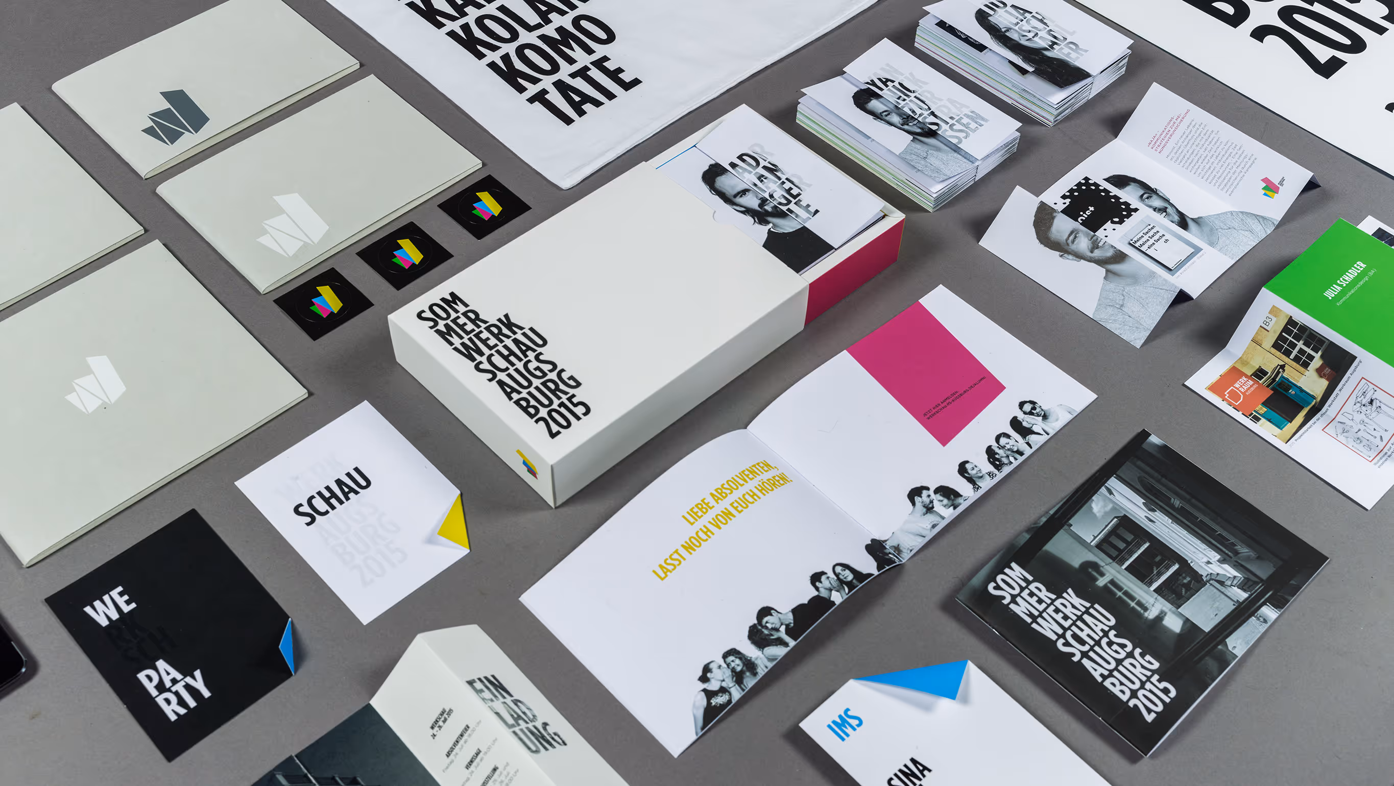 Grafikdesign-Printmaterialien verteilt auf grauem Untergrund mit Texten wie Sommerwerkschau Augsburg 2015.
